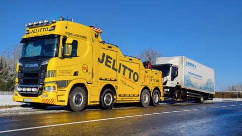 Gelber Schlepper schleppt LKW